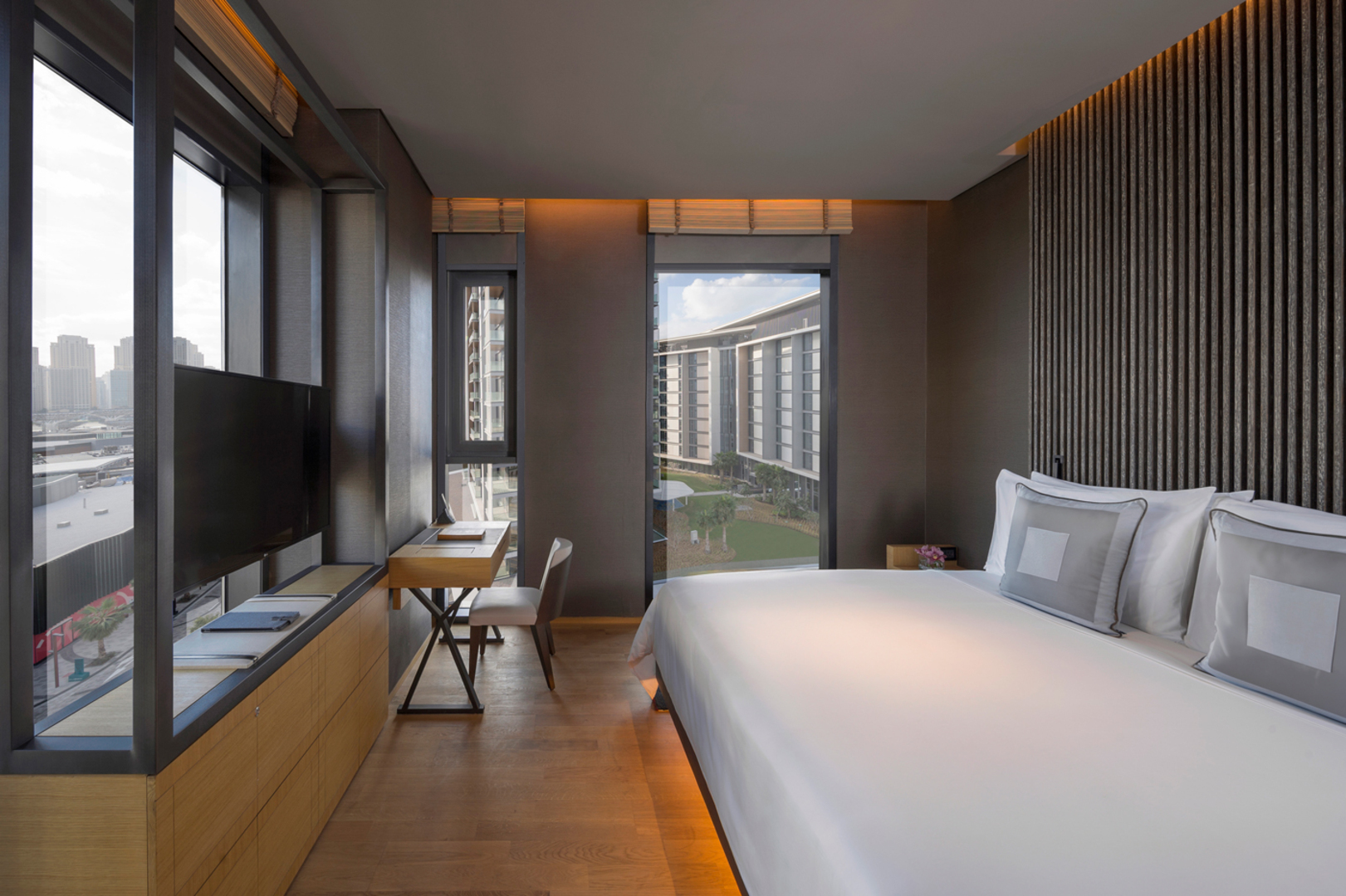 Luxurious 3-bedroom with a large bed, TV, and desk overlooking cityscape at Banyan Tree Dubai.